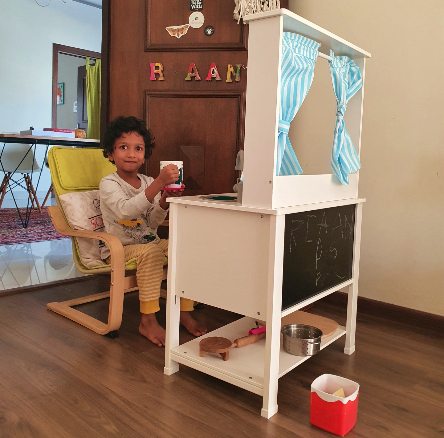 child sitting on a chair in front of his IKEA toy kitchen