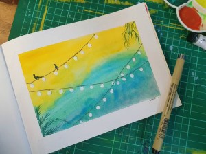 Gouache painting of birds on a wire with art supplies around the art journal sketchbook