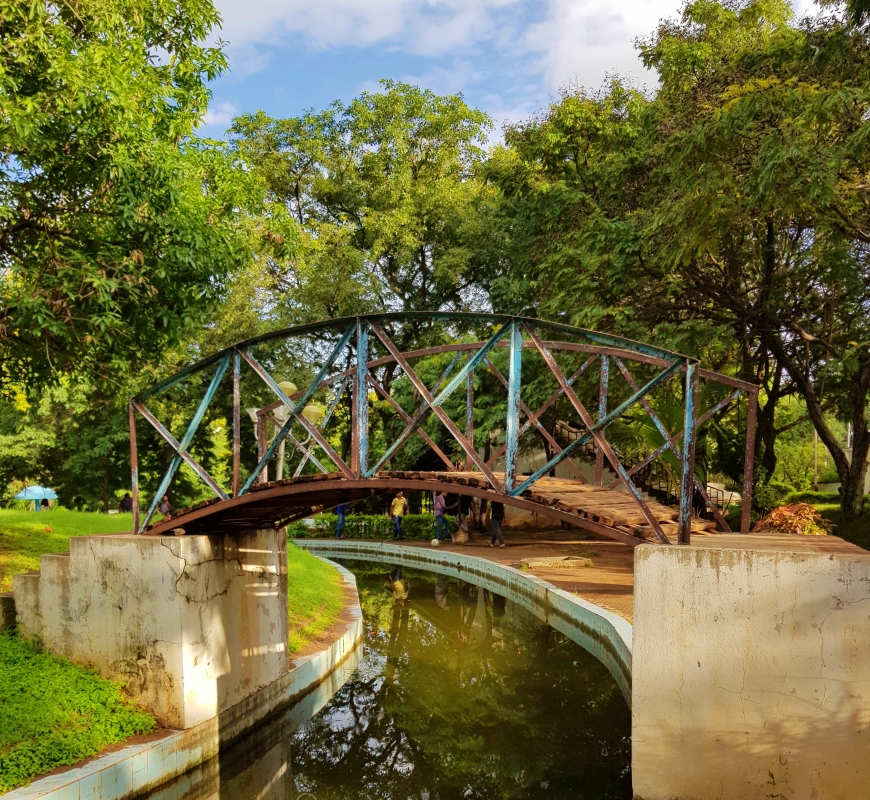 metal bridge over a small moat in a park