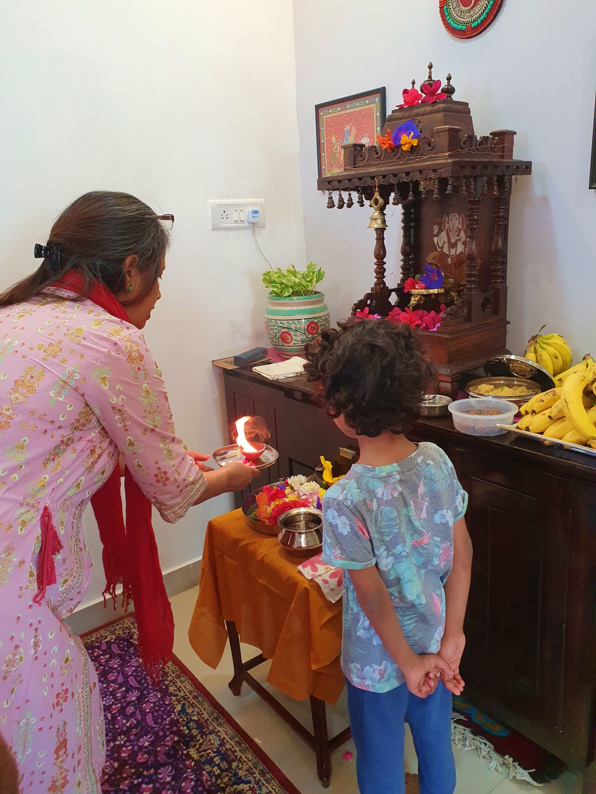 Child learning Hindu religious customs and praying with his grandmother