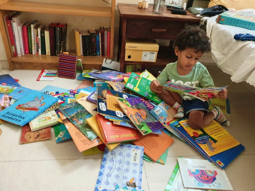 child with a pile of books on the floor