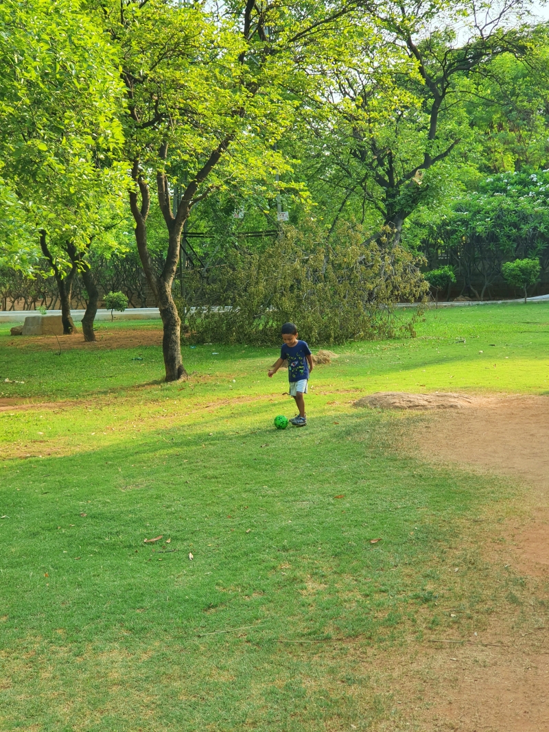 kid kicking a ball around in a park