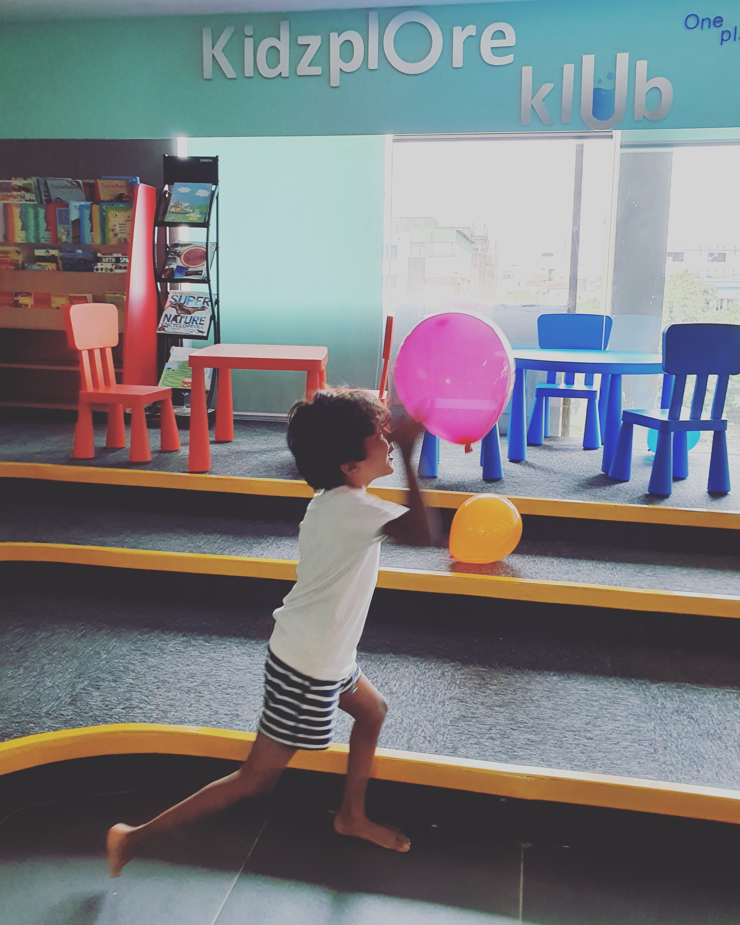 child playing with balloons in an activity centre for kids