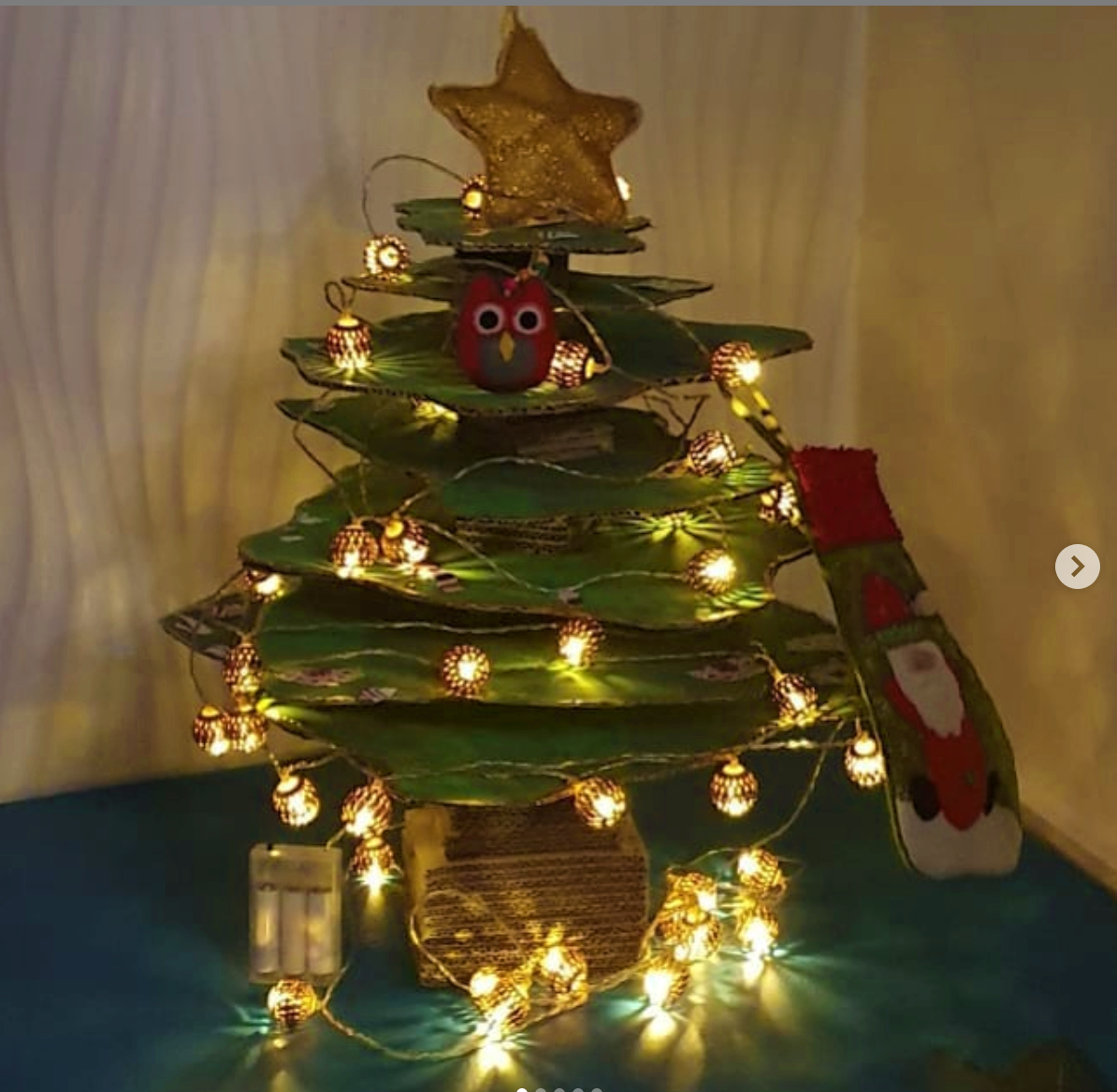 DIY Christmas tree made with cardboard packaging, lit up with a string light and decorated with toys