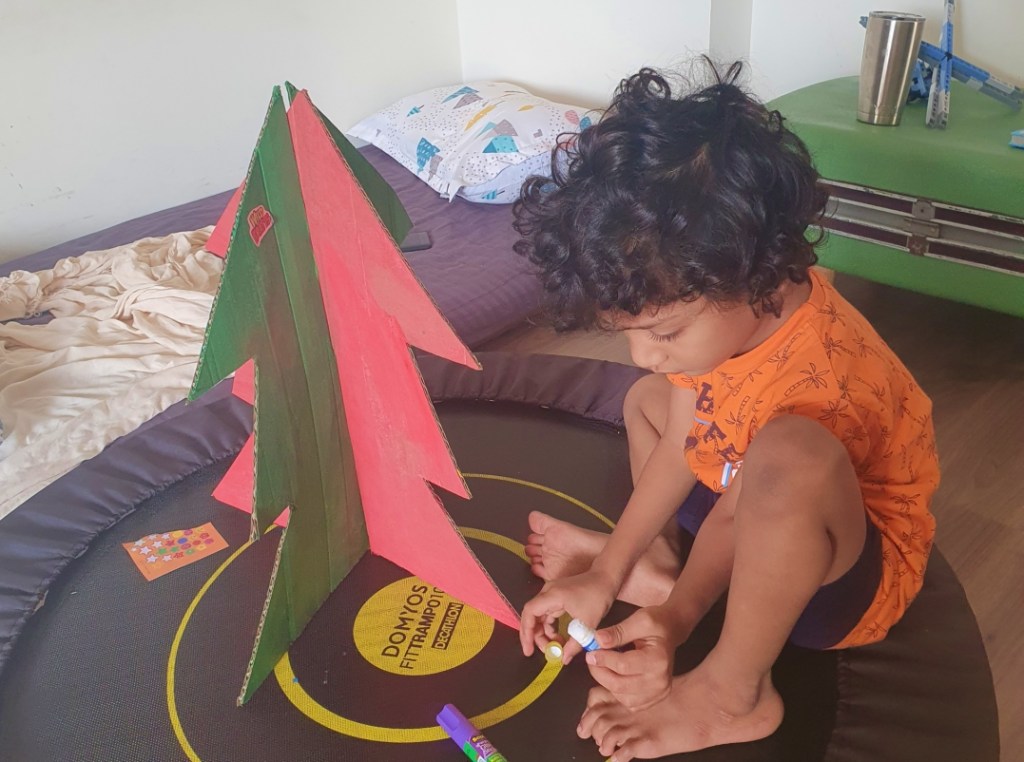 child decorating a cardboard christmas tree