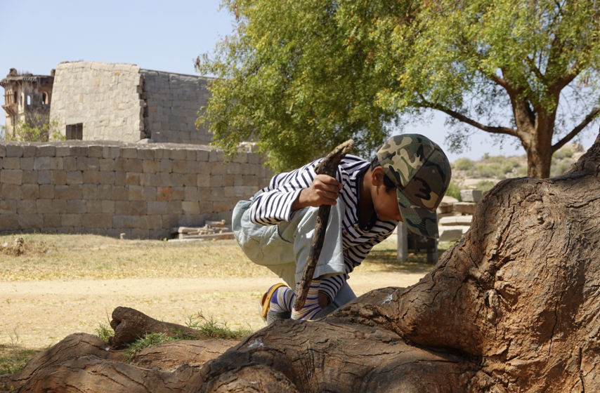 child exploring and digging for sticks and stones to pass the time