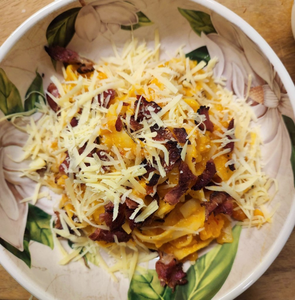 Bowl of pasta. Butternut squash fettuccine with sambal oelek and bacon bits and grated cheese