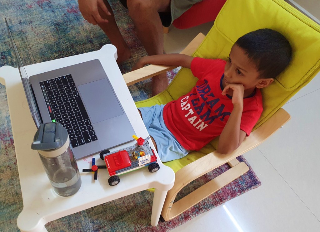 Child sitting on a chair in front of a laptop attending online classes