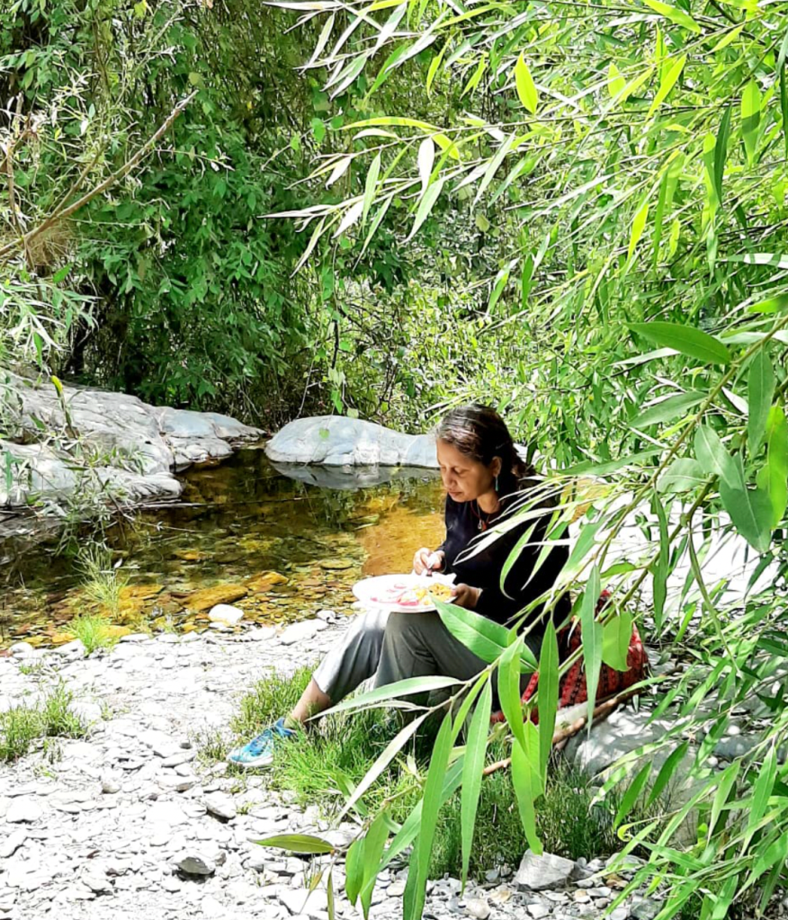woman sitting by the waterfall having lunch