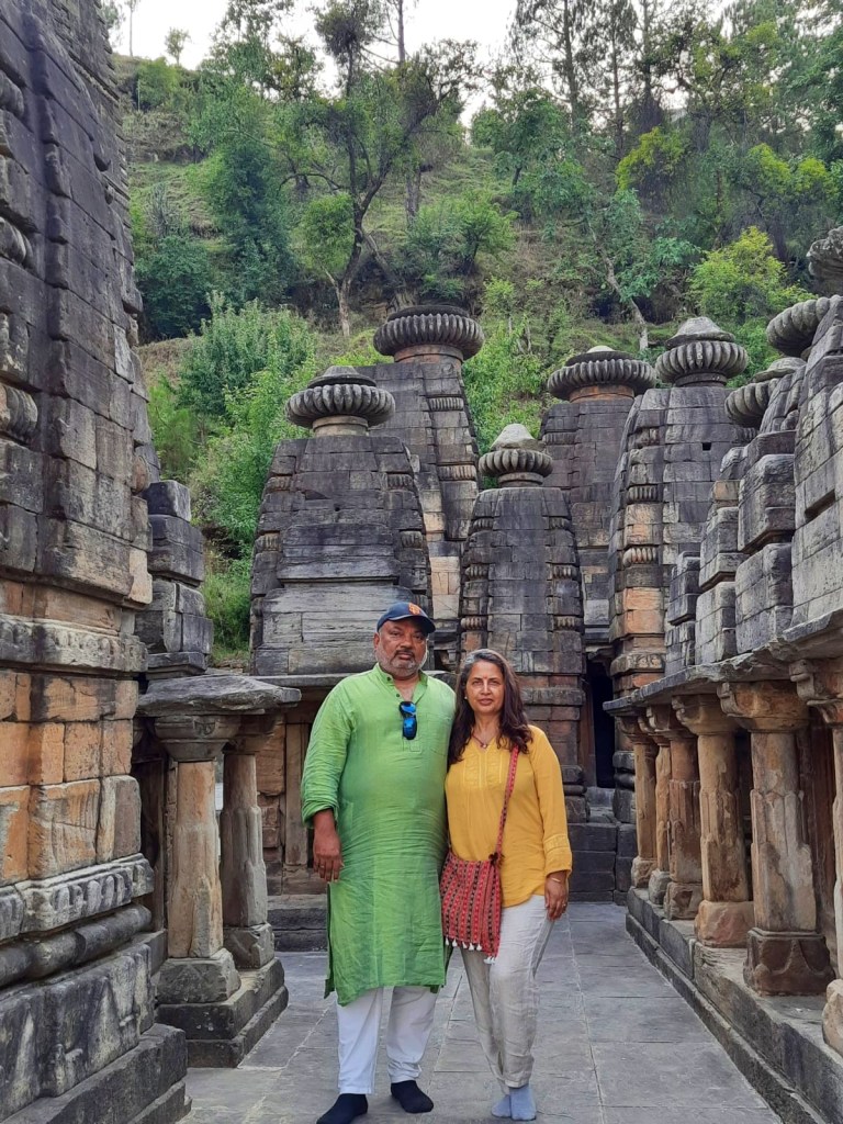man in green kurta and woman in yellow shirt at sun temple with ancient stone structures and pillars around them