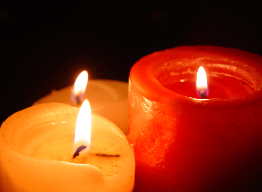 3 lit candles in red and yellow against a black background