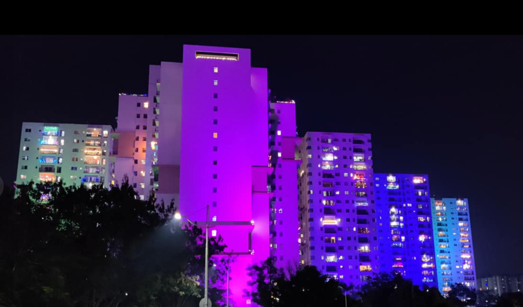 Buildings and homes lit up in shades of blue and purple for Diwali against a night sky