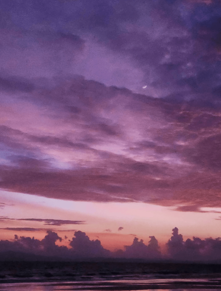 Shades of purple sky with a sliver of the crescent moon visible