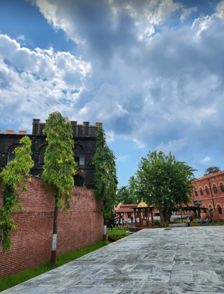 the cellular jail in red bricks with green trees all around, and with blue skies with white clouds