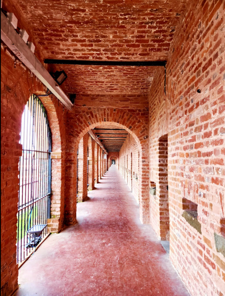 the long red brick corridor of the cellular jail, with rows and rows of tiny prison cells