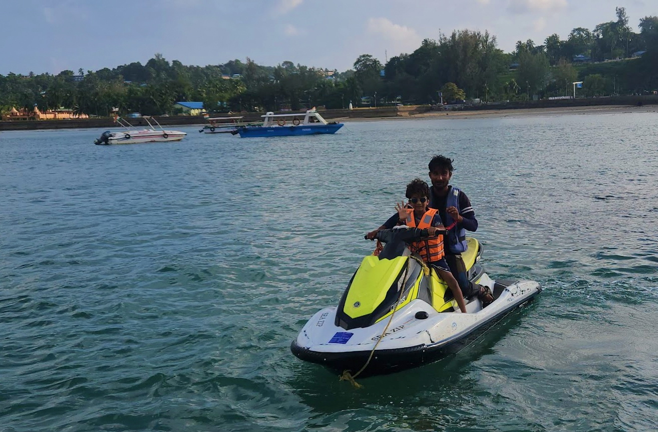 Child on a jet ski with an instructor waving excitedly