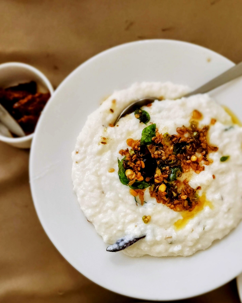 a plate of curd rice topped with tempering of spices