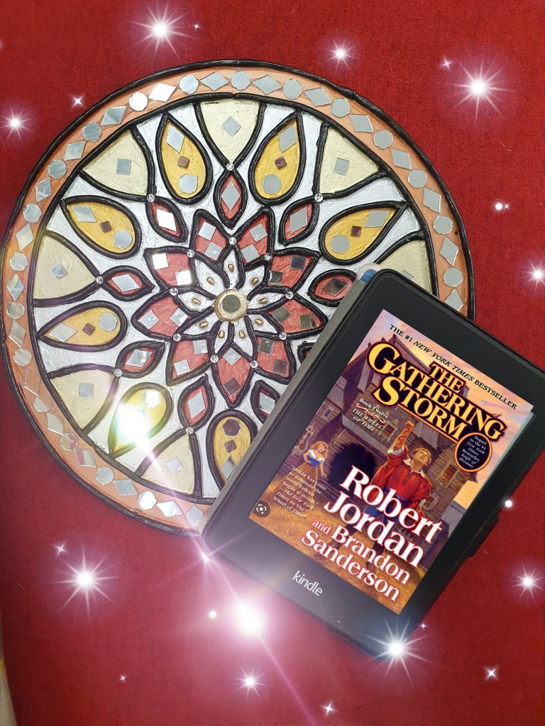 Robert Jordan's Wheel of Time Book 12 The Gathering Storm cover on a Kindle Paperwhite set on a circular work of lippan art on a red background