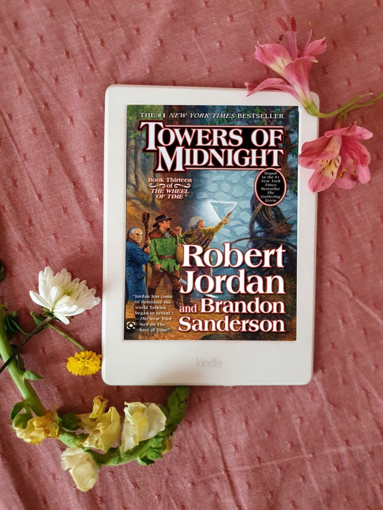 Robert Jordan's Wheel of Time Book 13 Towers of Midnight on Kindle on a pink fabric with flower stems on the side