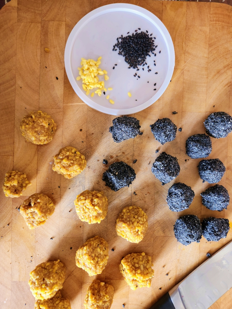 Moong dal and black sesame balls ready on a wooden board ready to be filled into the mochi dough