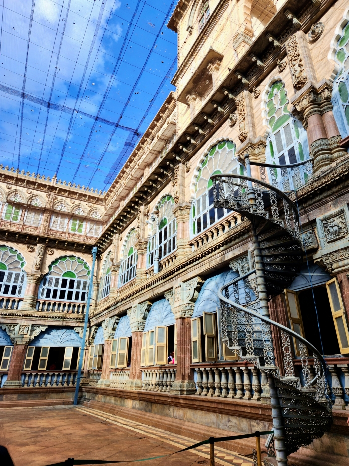 the wrestling artium of the mysore palace with a winding staircase and windows of the palace overlooking the arena