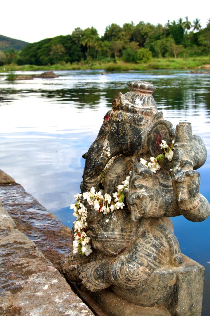 ganesh idol carved in stone at the edge of a river