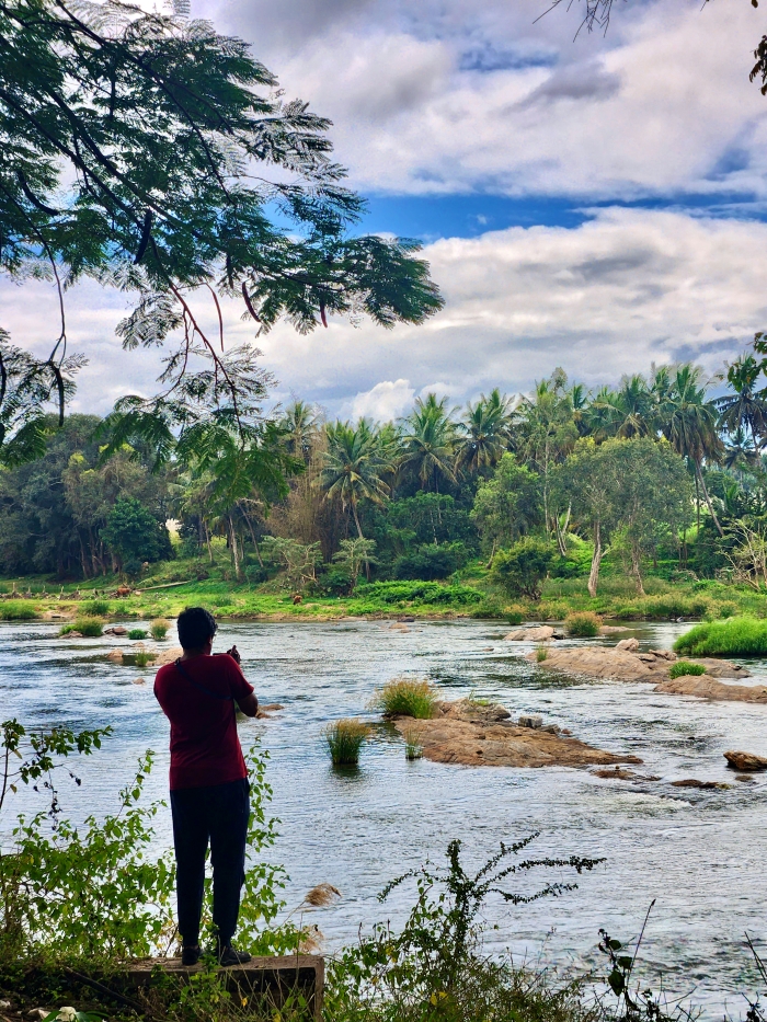 man standing at the edge of a river taking pictures
