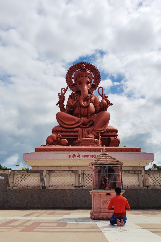 man praying in front of large ganesh statue