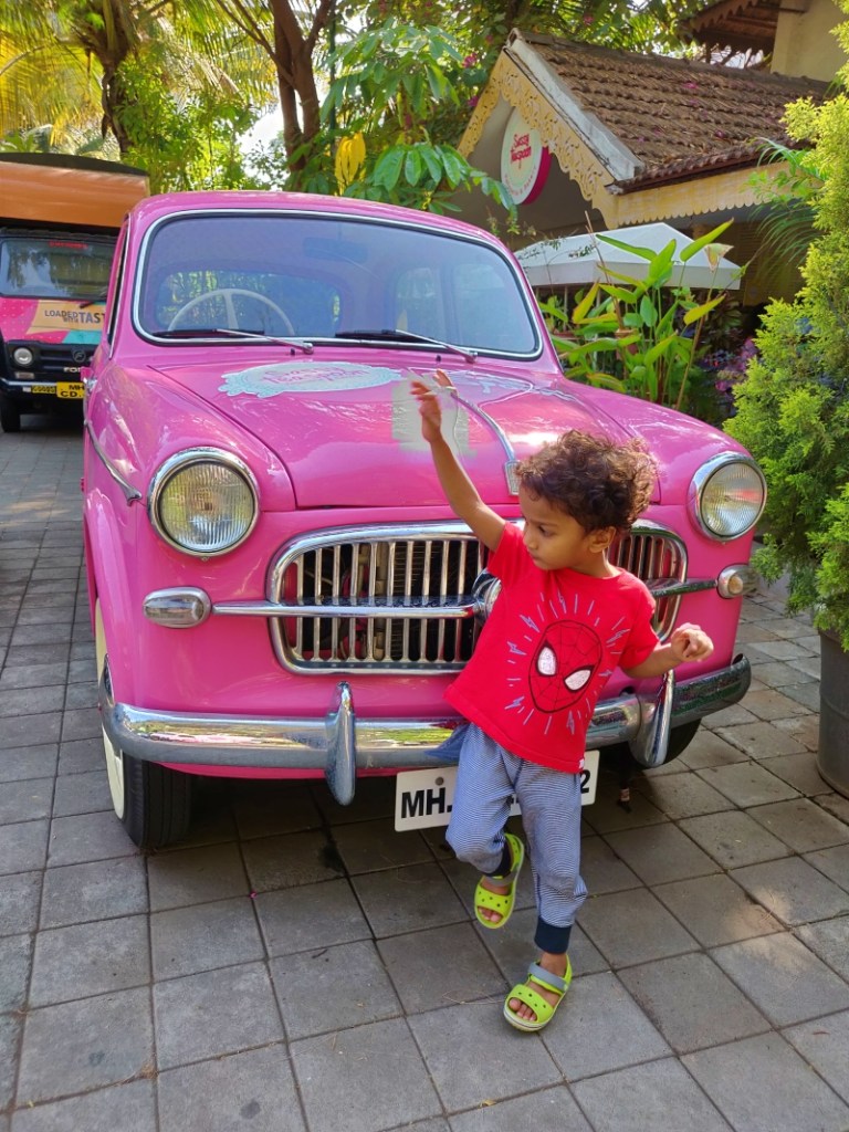 boy in front of pink ambassador car