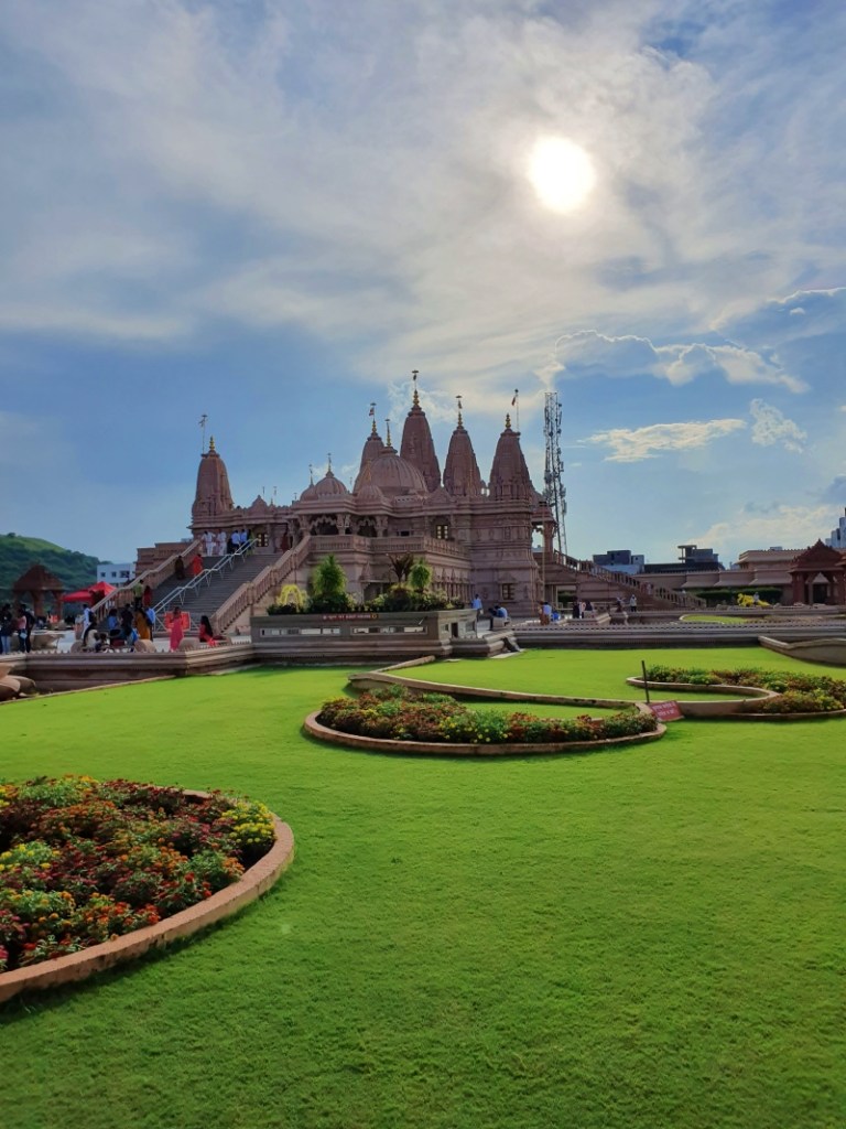 large hindu temple with lush lawns and blue sky with bright sun