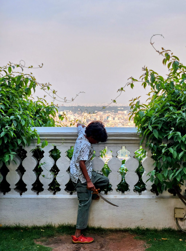 child with toy sword looking over palace walls towards the city