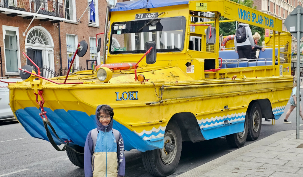 boy in jacket in front of the viking splash tours bus shaped like a boat