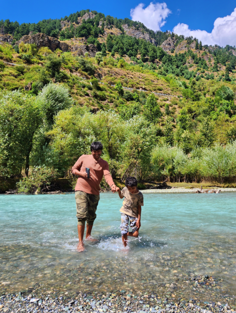 father and son dip their feet in lidder river in Betaab Valley