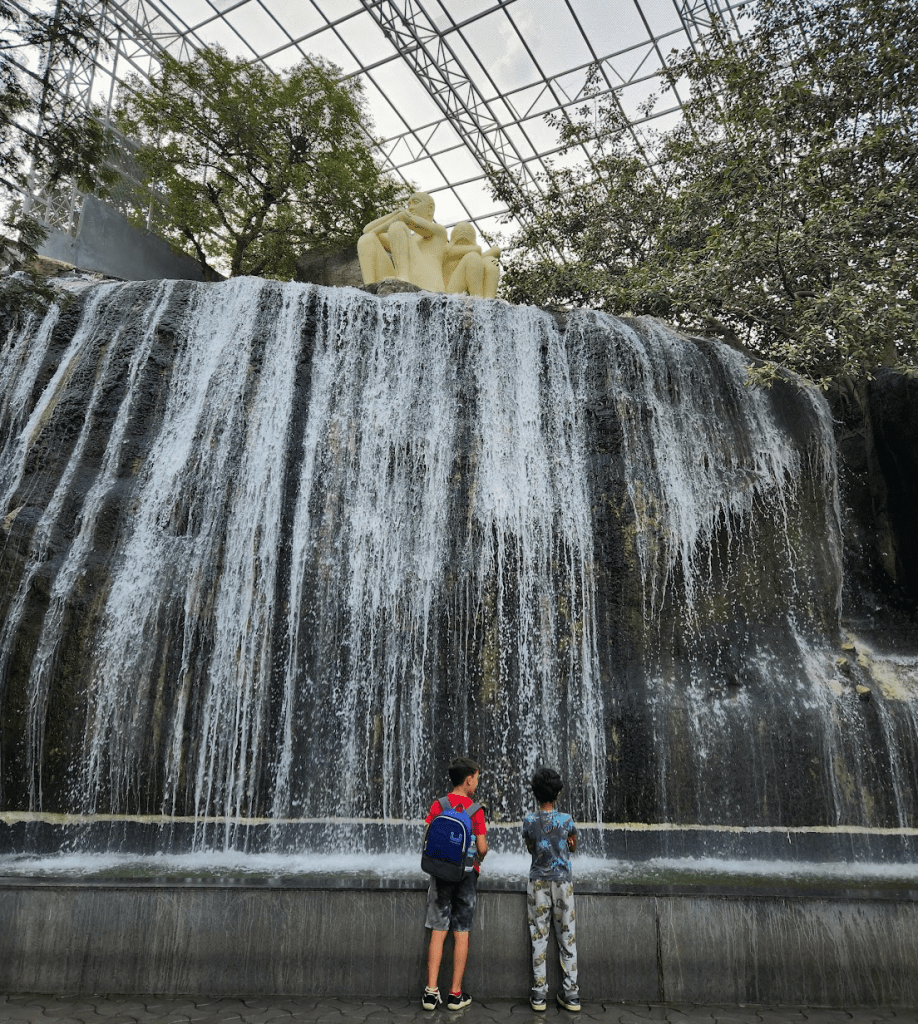 Kids in front of man-made waterfall at Ramoji Film City Hyderabad Aviary