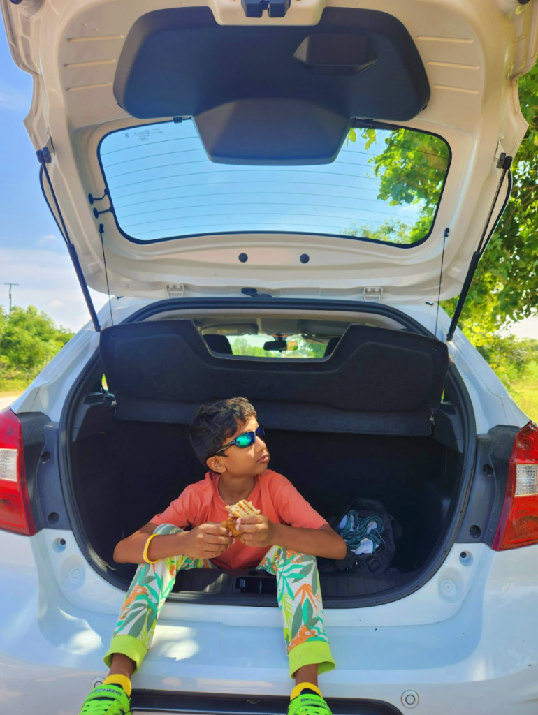 road trip kid eating in the trunk of the car